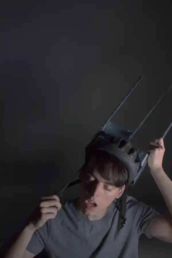 A guy removes a fork shaped helmet from his head