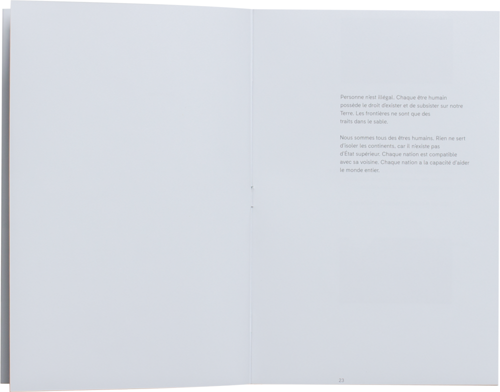 Livre ouvert. Simple composition avec un petit texte sur la page de droite. On y lit le texte suivant. Personnne n’est illégal. Chaque être humain possède le droit d’exister et de subsister sur notre Terre. Les frontières ne sont que des traits dans le sable. Nous sommes tous des êtres humains. Rien ne sert d’isoler les continents, car il n’existe pas d’État supérieur. Chaque nation est compatible avec sa voisine. Chaque nation a la capacité d’aider le monde entier.