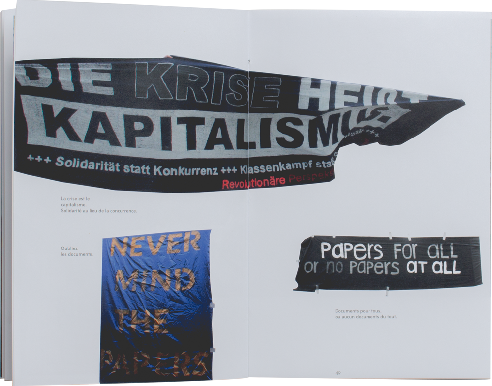 Livre ouvert. Composition de trois bannières différentes. Les bannières sont découpées et semblent flotter comme des drapeaux sur les pages. Sur l'une d'entre elles, l'on peut lire en allemand 